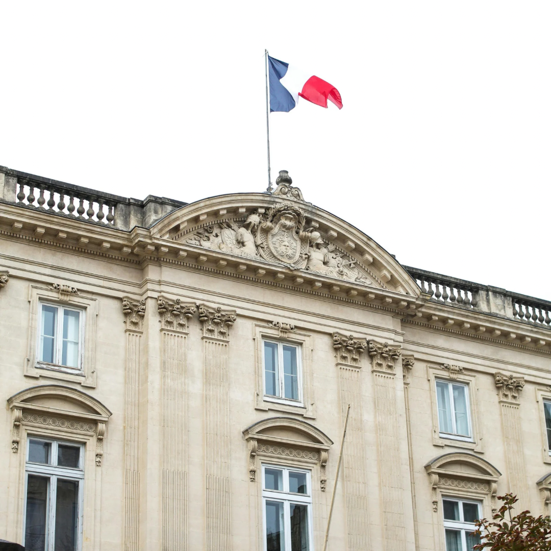 Façade de bâtiment officiel en pierre avec drapeau français sur le toit, style classique.